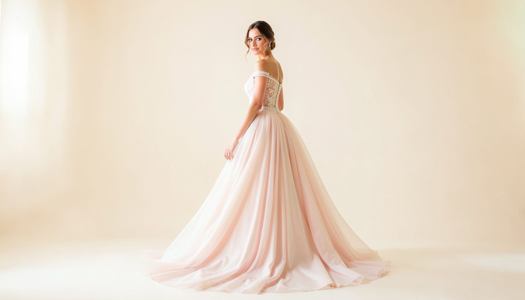 Bride in a flowing ethereal gown posed in a soft-lit studio, cream and blush tones